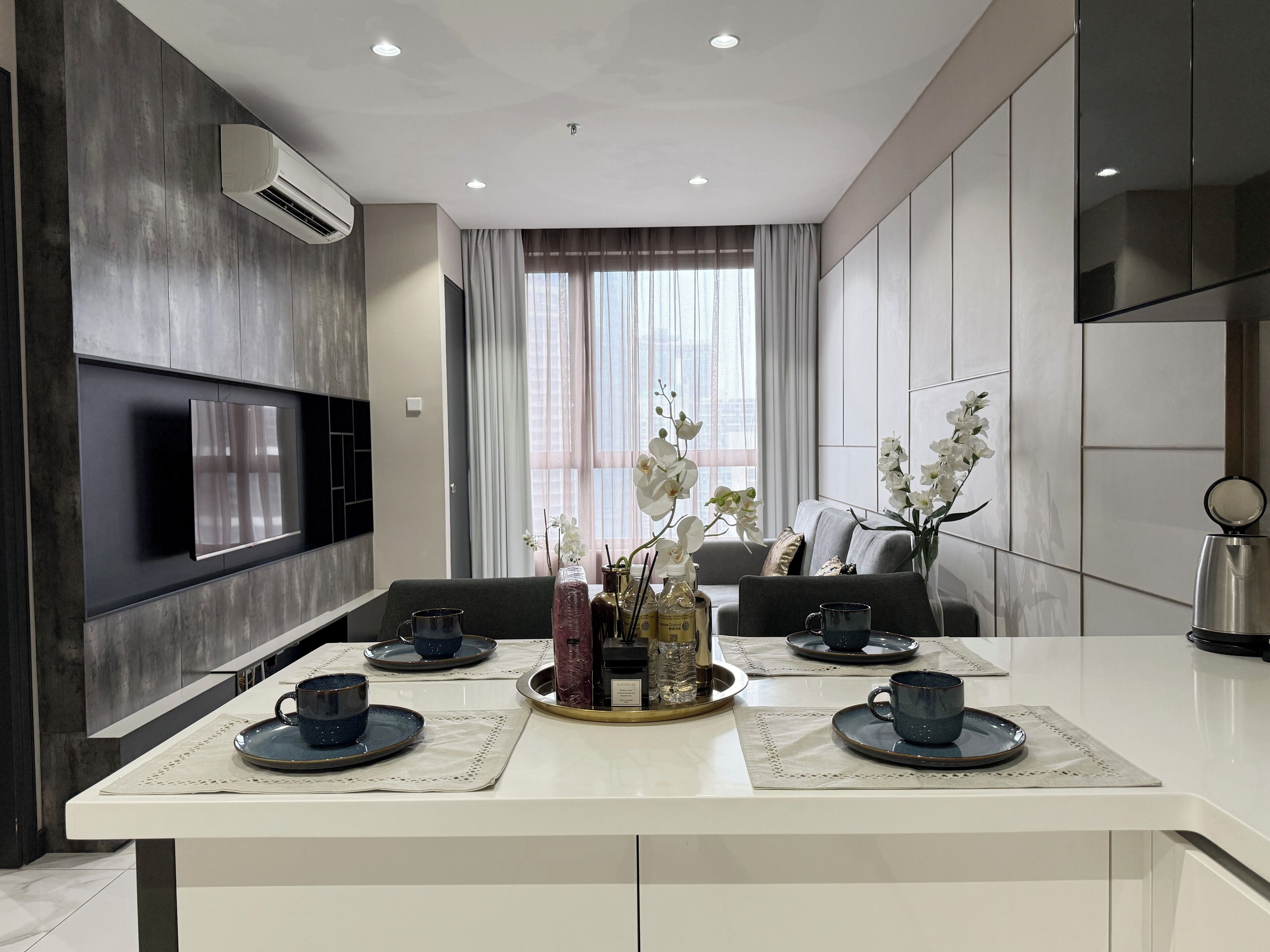 Una cocina moderna con una isla central, electrodomésticos integrados y un amplio ventanal con cortinas.
