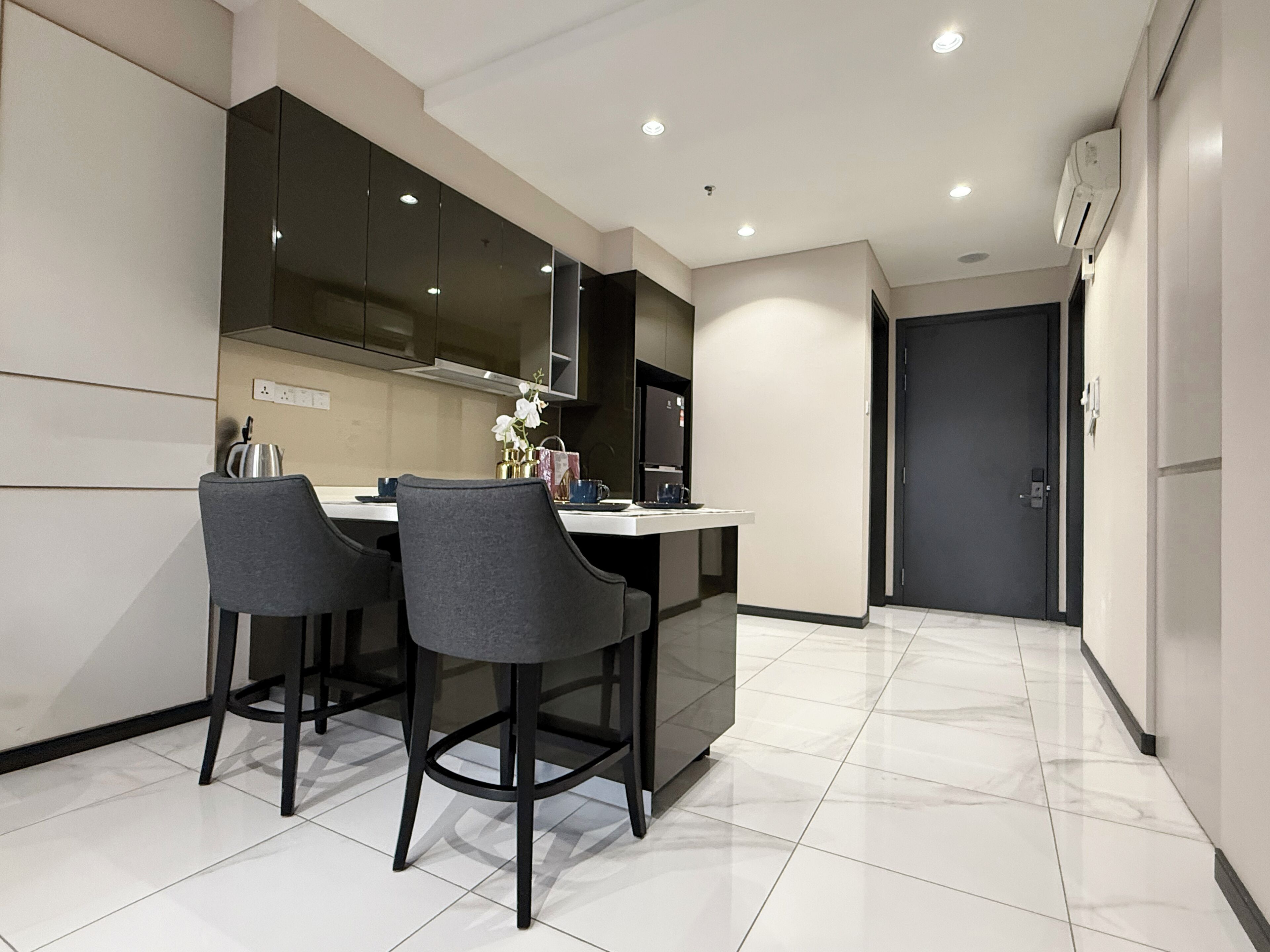 A modern kitchen with two bar stools, a dining table, and a black cabinet.