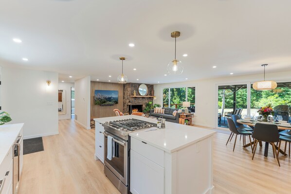 A spacious kitchen with a central island, a dining area with a table and chairs, and a fireplace.