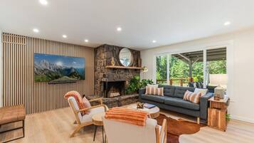Una sala de estar moderna con una chimenea de piedra, un cuadro grande y una zona de estar acogedora con un sofá y sillones.