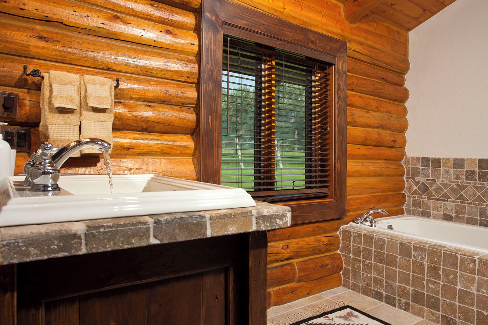 Un baño con pared de madera, una ventana con persianas, un lavamanos y una bañera.
