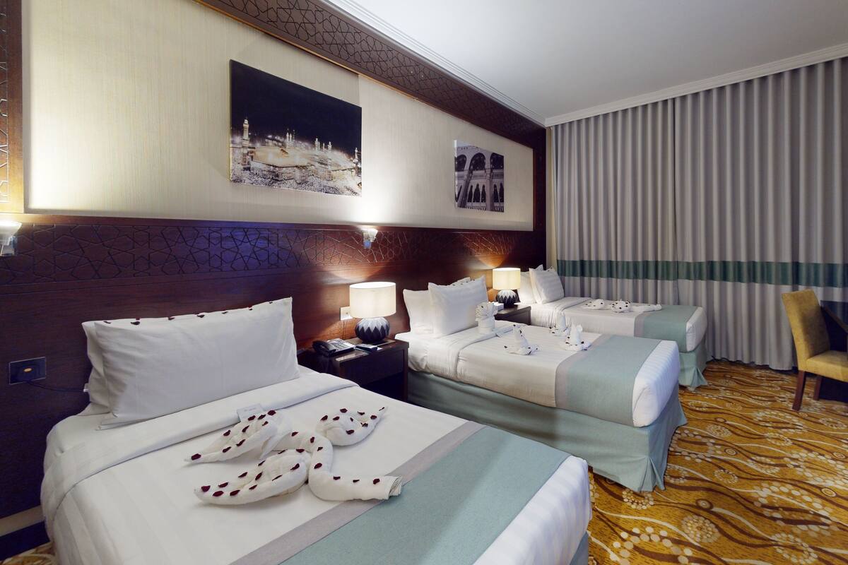 A hotel room with two beds, a television, a desk, and a chair.