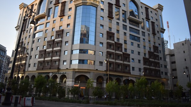 Un hotel de varios pisos con fachada moderna, amplias ventanas y una llamativa sección curva de cristal.