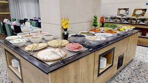 Un bufé con diferentes opciones de comida y un área de comedor con sillas y mesas.