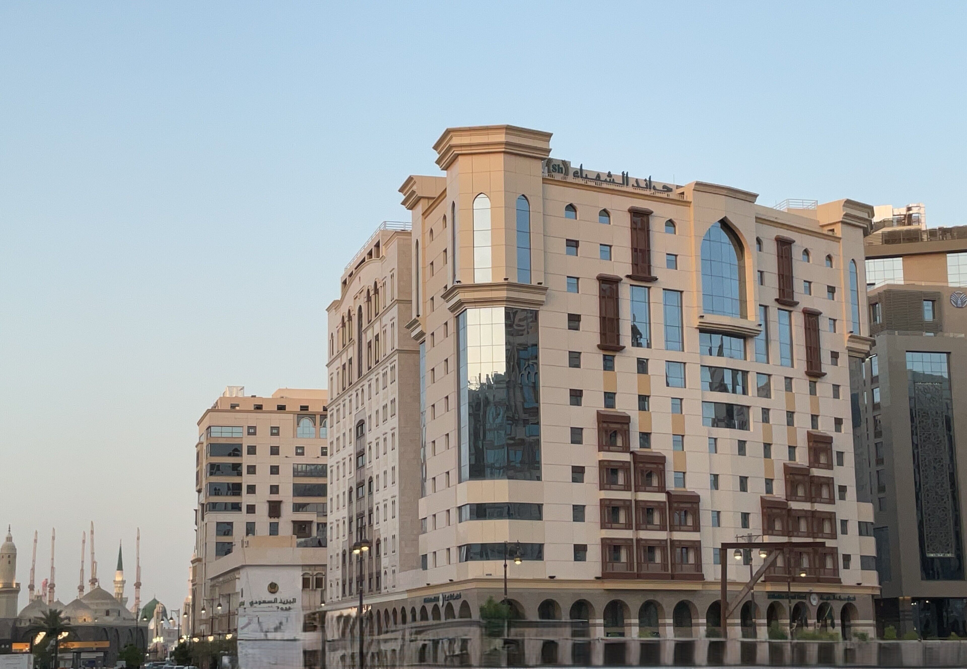 A multi-story hotel with a modern architectural design, featuring arched windows and a central courtyard.