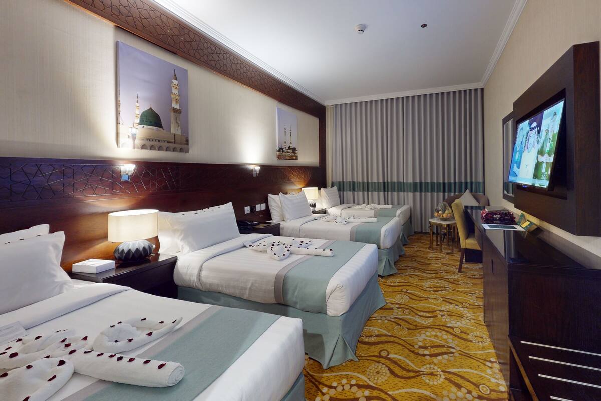 A hotel room with two beds, a TV, a desk, and a small table.