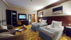 Una habitación de hotel con dos camas, televisión, escritorio y una silla.