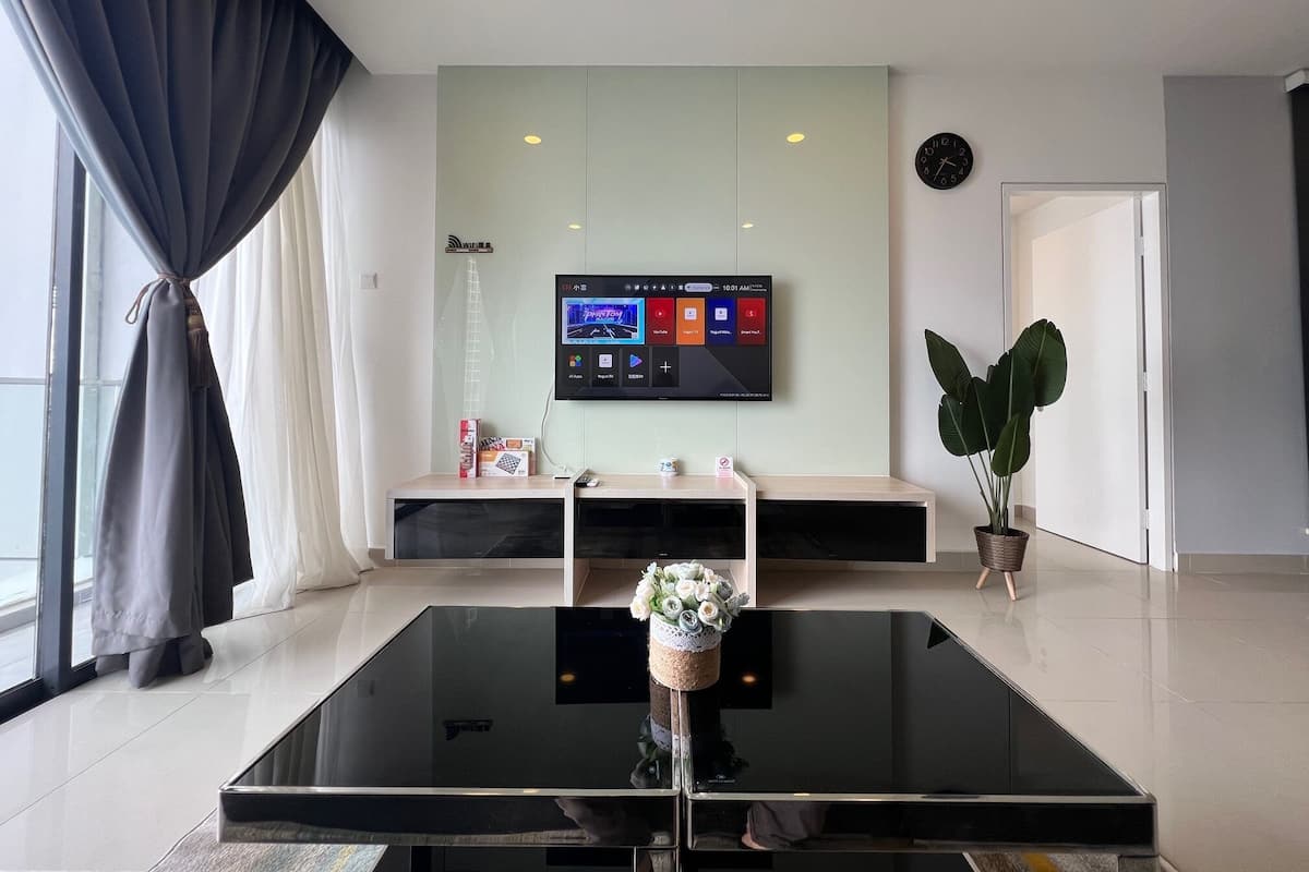 Una sala de estar moderna con un televisor de pantalla plana en la pared, una mesa de centro de vidrio y una planta en maceta.