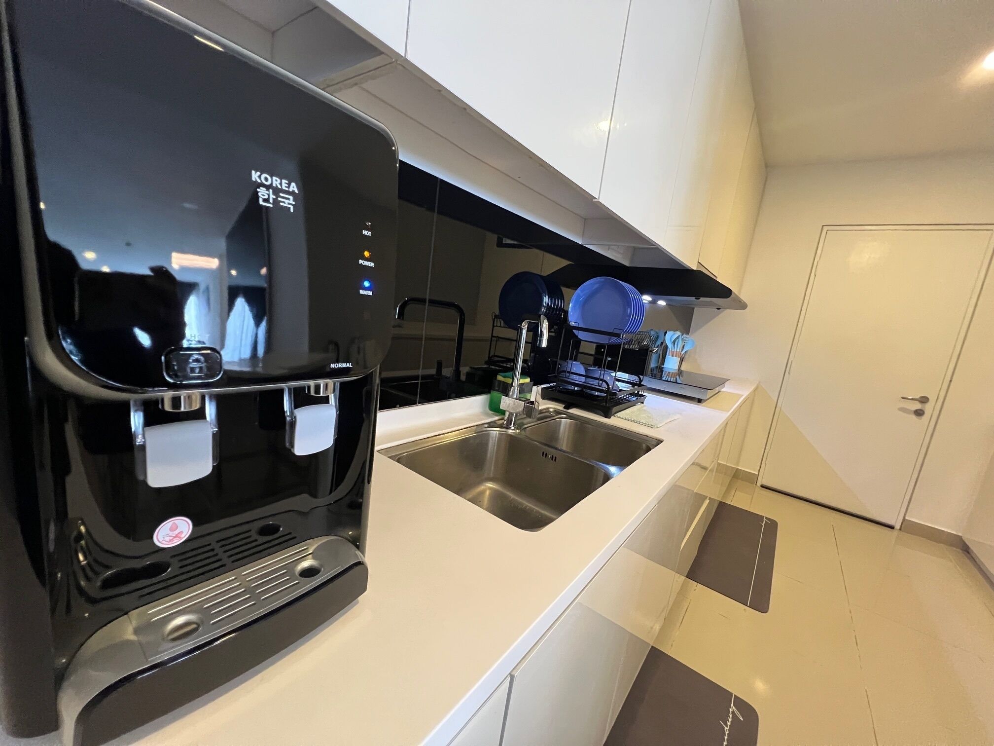 Una cocina moderna con cafetera integrada, pileta de acero inoxidable y escurreplatos.