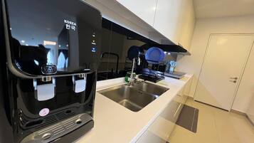 Una cocina moderna con cafetera integrada, pileta de acero inoxidable y escurreplatos.