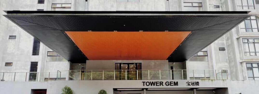 Un edificio moderno con un llamativo toldo naranja y el letrero "TOWER GEM".