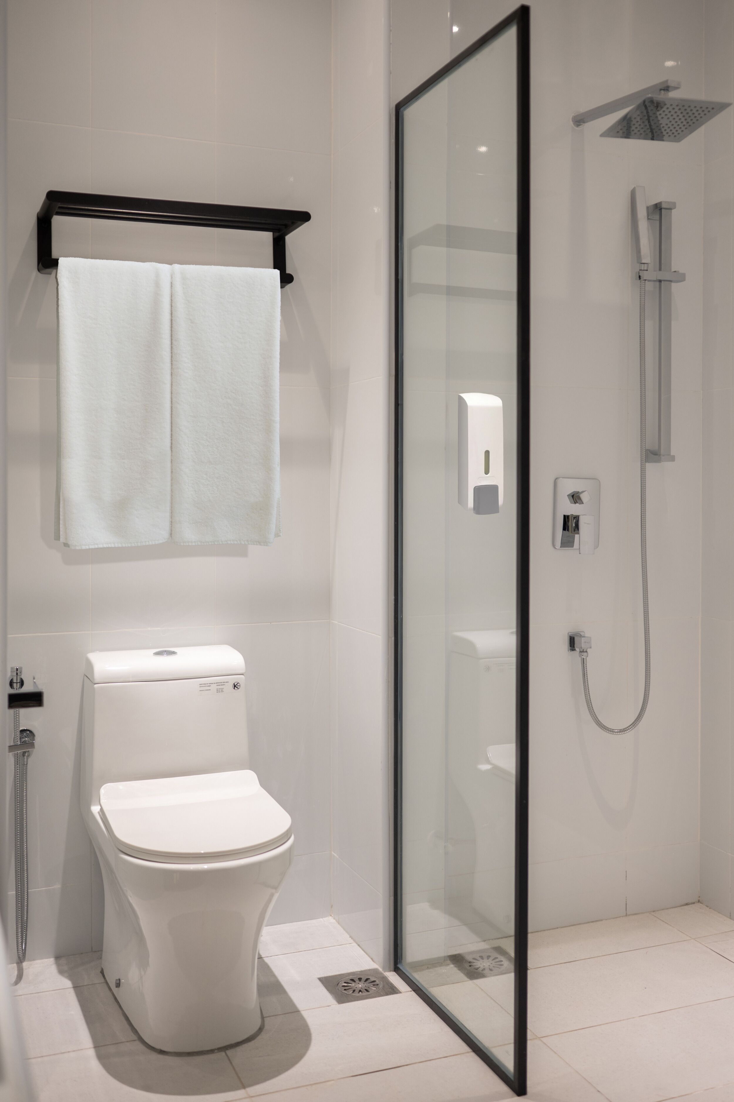 A modern bathroom with a toilet, a glass-enclosed shower, and a towel rack.