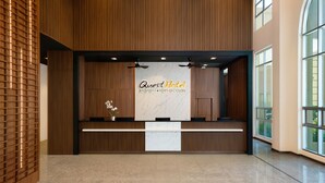 A reception desk with a marble top, wooden paneling, and a sign reading "Quest Hotel Midport, Port Dickson." - Quest Hotel Midport Port Dickson (Port Dickson)