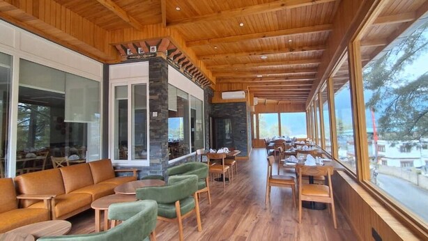 A spacious indoor area with wooden flooring, green and brown seating, and large windows offering views of the outside. - Bhutan Peaceful Residency and Spa (Thimphu)