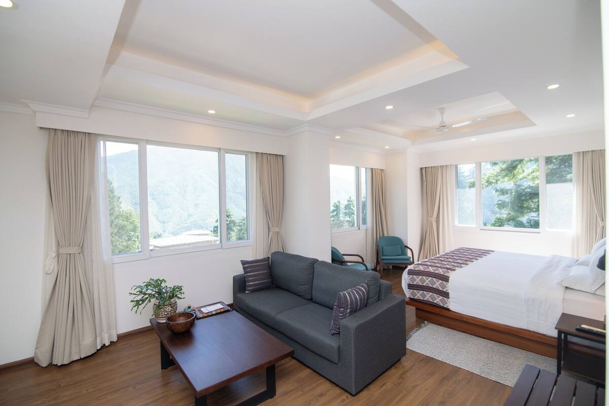 A modern hotel room with a sofa, a bed, a desk, and a chair.