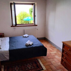 Cozy retreat with a single bed, window, and radiator, offering a view of lush greenery.