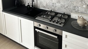 Une cuisine moderne avec des meubles de couleur bois foncé, un évier noir, une cuisinière à gaz et un four.