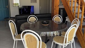 A dining area with a round table, white chairs, and a wooden staircase. - Vacation home 300 m from the sea St Denis D'oleron (Saint-Denis-d'Oléron)