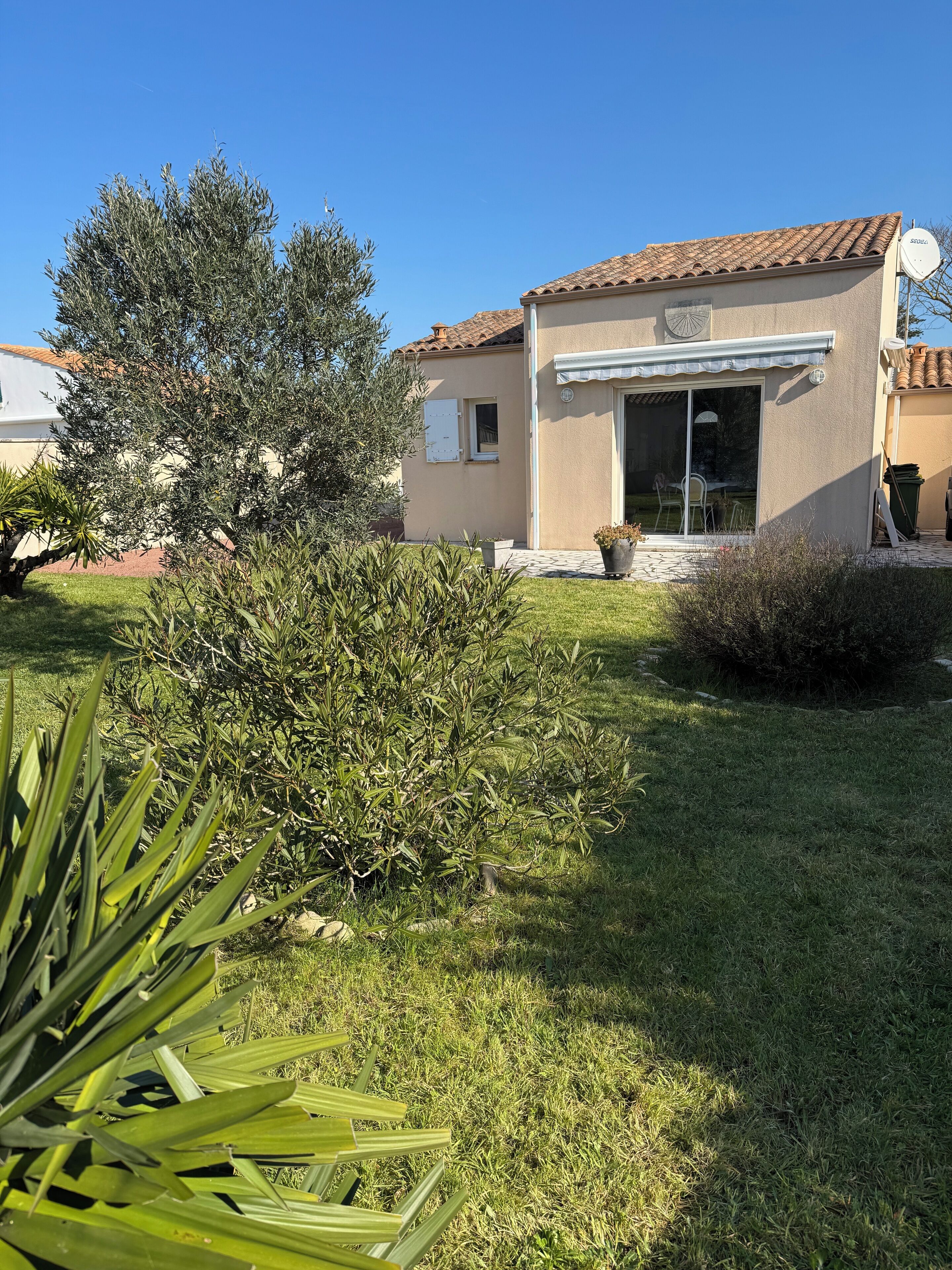Une maison avec un toit en tuiles, un patio couvert et une pelouse.
