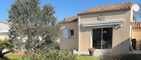 A house with a tiled roof, a covered patio, and a lawn.