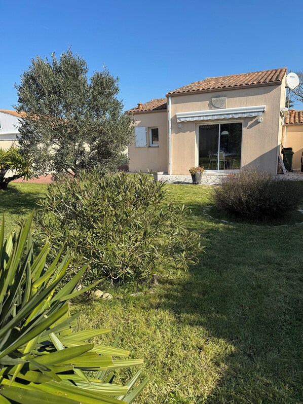 A house with a tiled roof, a covered patio, and a lawn. - Vacation Home 300 m from the Sea in Saint-Denis-d'Oléron (Saint-Denis-d'Oléron)