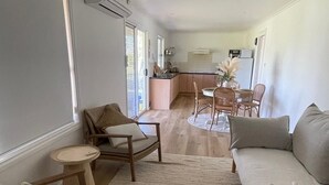 Un grand espace de vie comprenant un canapé, des fauteuils, une petite table et une cuisine à l’arrière-plan.