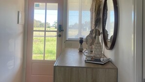 Un couloir avec une porte en bois, un miroir et un luminaire suspendu de style rustique.