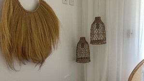 Une chambre avec un lit, une décoration murale en macramé et deux lampes en osier.