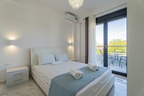 Ein modernes Schlafzimmer mit einem großen Bett, einem Nachttisch, einem Fenster mit Blick ins Freie und einer Klimaanlage.