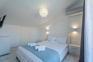 A modern bedroom with a large bed, bedside tables, a wardrobe, and a ceiling light fixture.