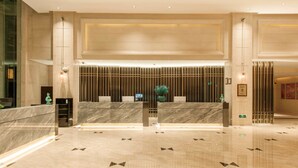 A modern hotel lobby with a reception desk, seating area, and a decorative wall. - Pagoda Hotel Shanghai Baixia near Jingan Temple (Shanghai)