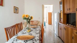 Una cocina compacta con armarios de madera, una mesa de comedor con sillas y un florero con flores.