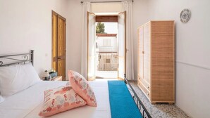 Un dormitorio con cama, almohadas, un armario y vistas al balcón exterior.
