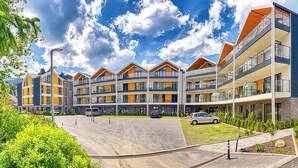A modern multi-story residential building with balconies, a paved courtyard, and surrounding greenery. - Apartamenty Sun & Snow Belle View (Szklarska Poreba)