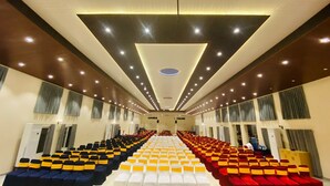 Un salón amplio con hileras de sillas, algunas con lazos amarillos y otras con lazos rojos.