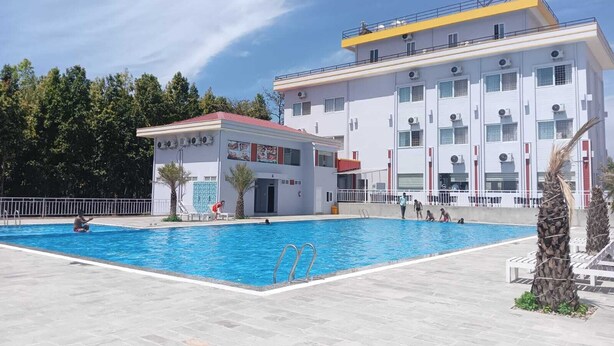Zona de piscina con un edificio al fondo.