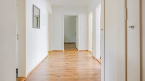 Un couloir doté d’un plancher en bois, de murs blancs et de portes donnant sur d’autres pièces.