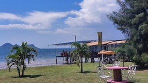 A beachfront property with a dining area featuring outdoor seating and a view of the ocean. - Lorateng' Resort Rusinga (Rusinga Island)