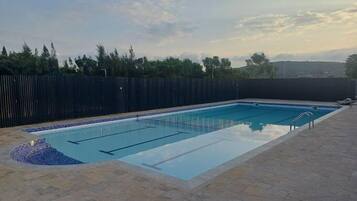 Relax by the pool surrounded by a deck and a fence, with a ladder for easy access.