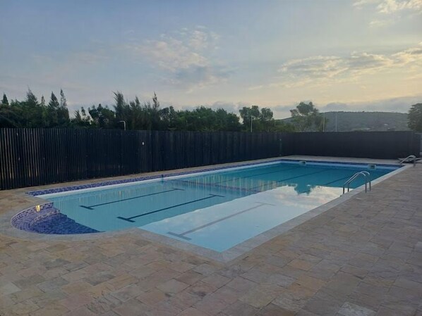 A rectangular swimming pool with clear blue water, surrounded by a tiled deck.