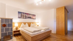 Een gezellige slaapkamer met een houten bed, een stenen openhaard en een schilderij van een besneeerd landschap.