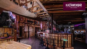 Een rustieke bar met houten wanden en een toog, met een bord waarop staat 