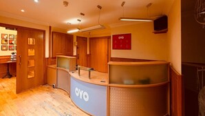Una zona de recepción con un mostrador de madera, un televisor montado en la pared y un letrero que dice