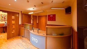 Una zona de recepción con un mostrador de madera, un televisor montado en la pared y un letrero que dice 