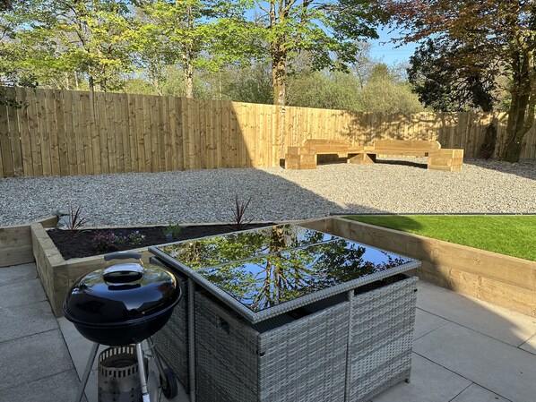 Une terrasse avec un barbecue, un bassin rectangulaire et une clôture en bois.