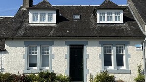 Un edifici de dues plantes amb teulada negra, parets blanques i porta negra. Hi ha dues finestres al pis superior i una al pis inferior.