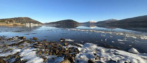 A rocky shoreline with a clear lake and distant mountains.