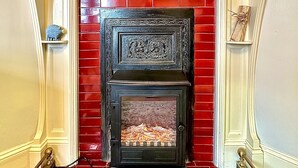Una llar de foc amb una paret de maó vermell, una cornisa decorativa i una petita figura a l'esquerra.