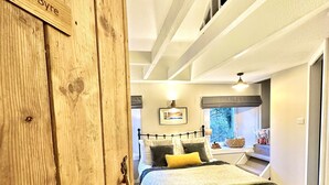 A bedroom with a bed, a window, and a wooden door with 'The Bye' on it.