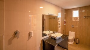 A modern bathroom with two sinks, a mirror, a toilet, and a trash bin. - goSTOPS Ooty (Ooty)